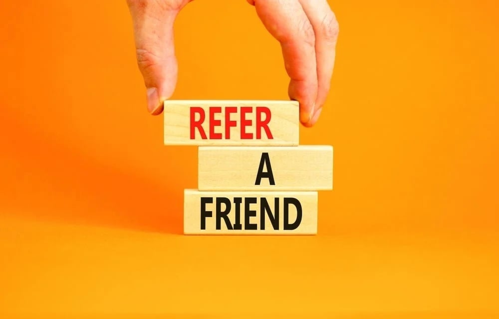 Hand stacking blocks with refer a friend text