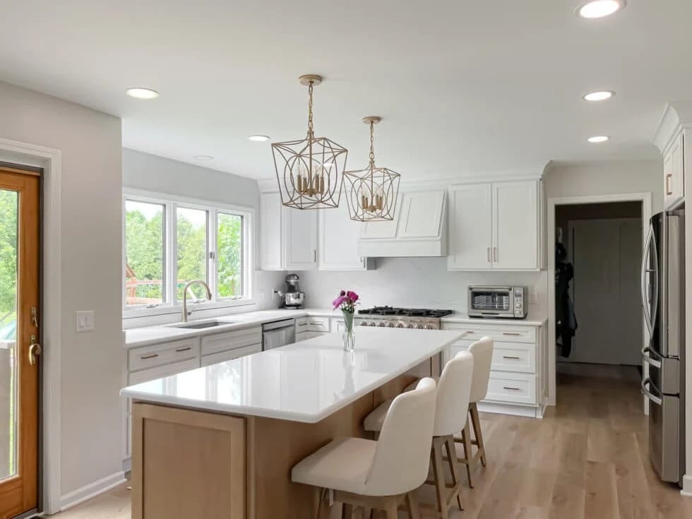 A modern kitchen with white cabinets and a large island with white barstools.