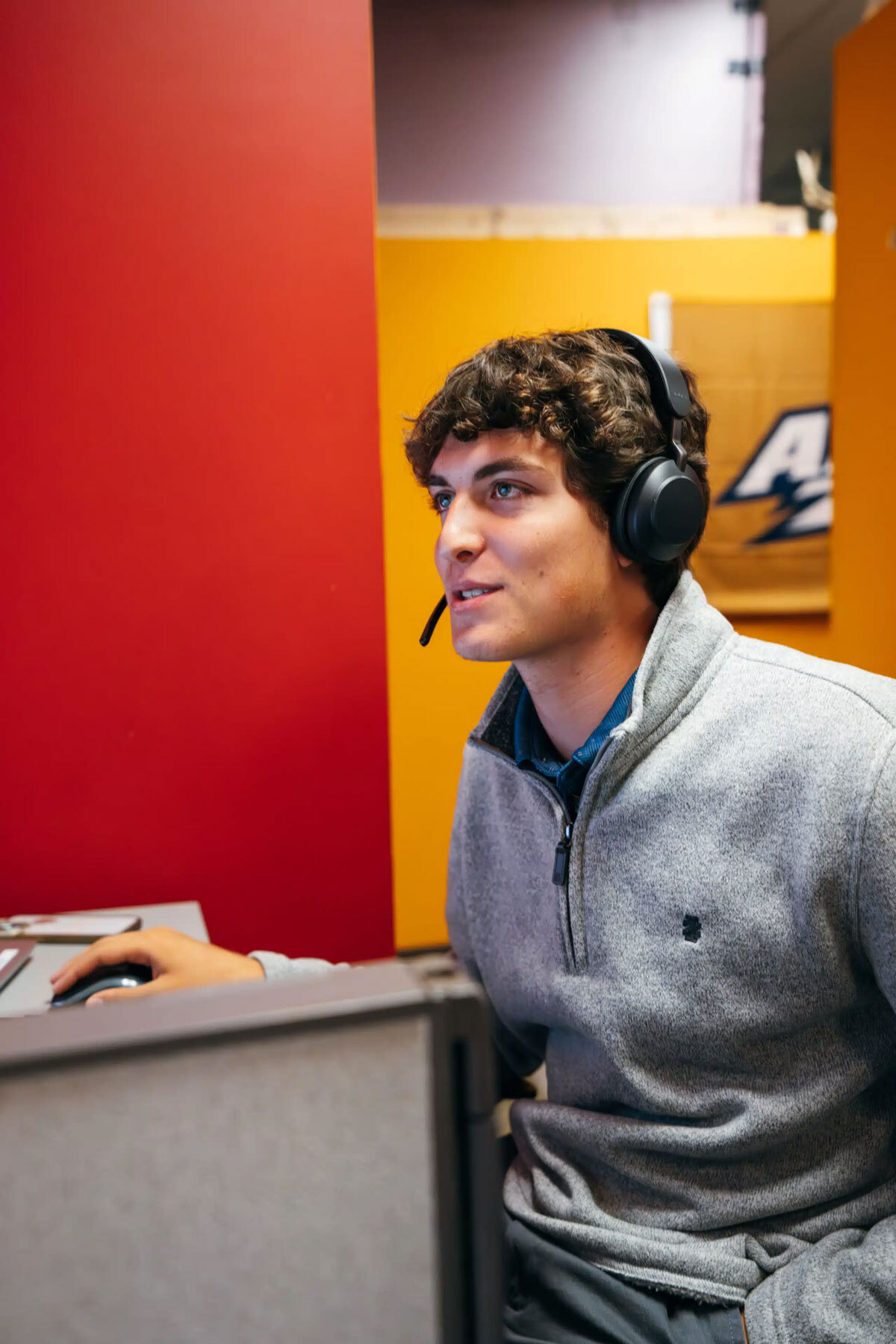 A young man with curly hair wearing a headset