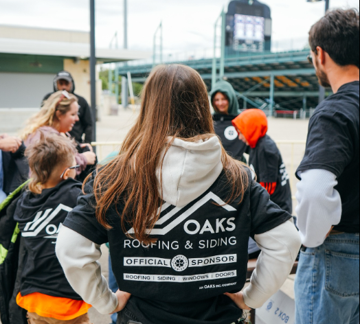 People wearing black shirts with Oaks Roofing & Siding logo. They appear to be a team or group.