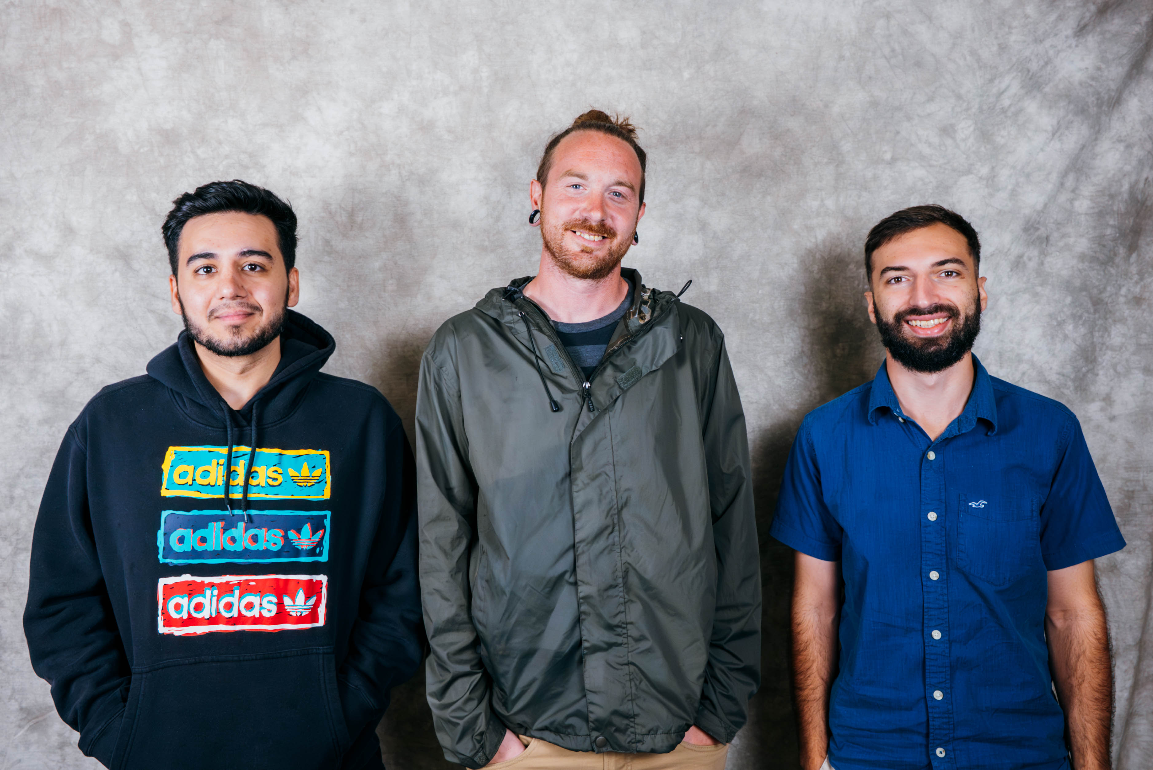 Three men posing for a photo. They are standing side by side.