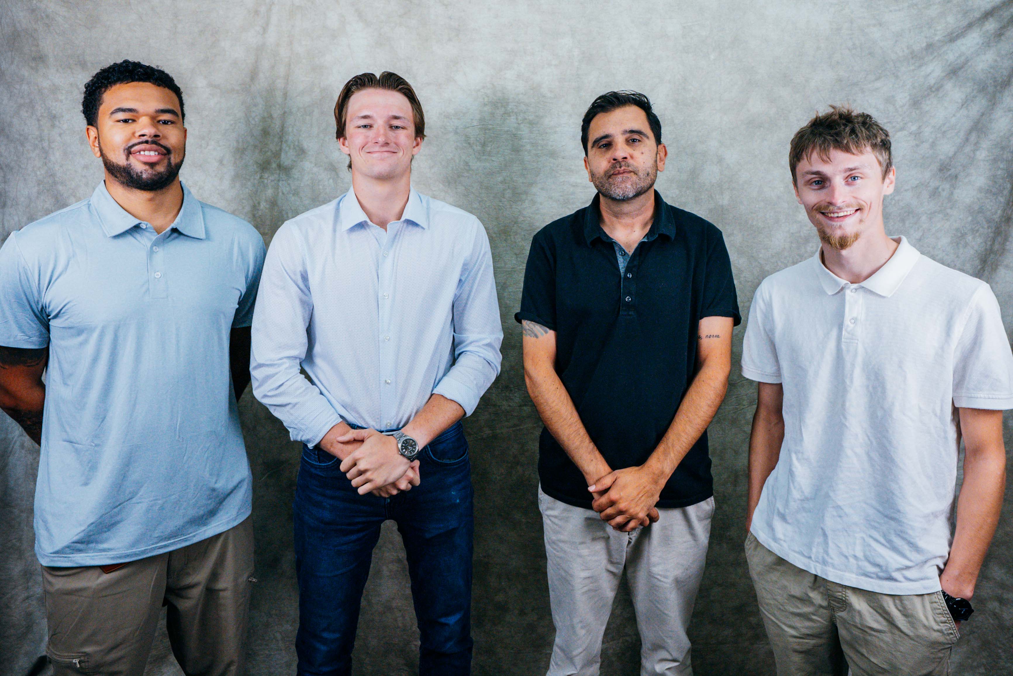 A diverse group of professionals posing together in a studio setting, showcasing teamwork and unity.
