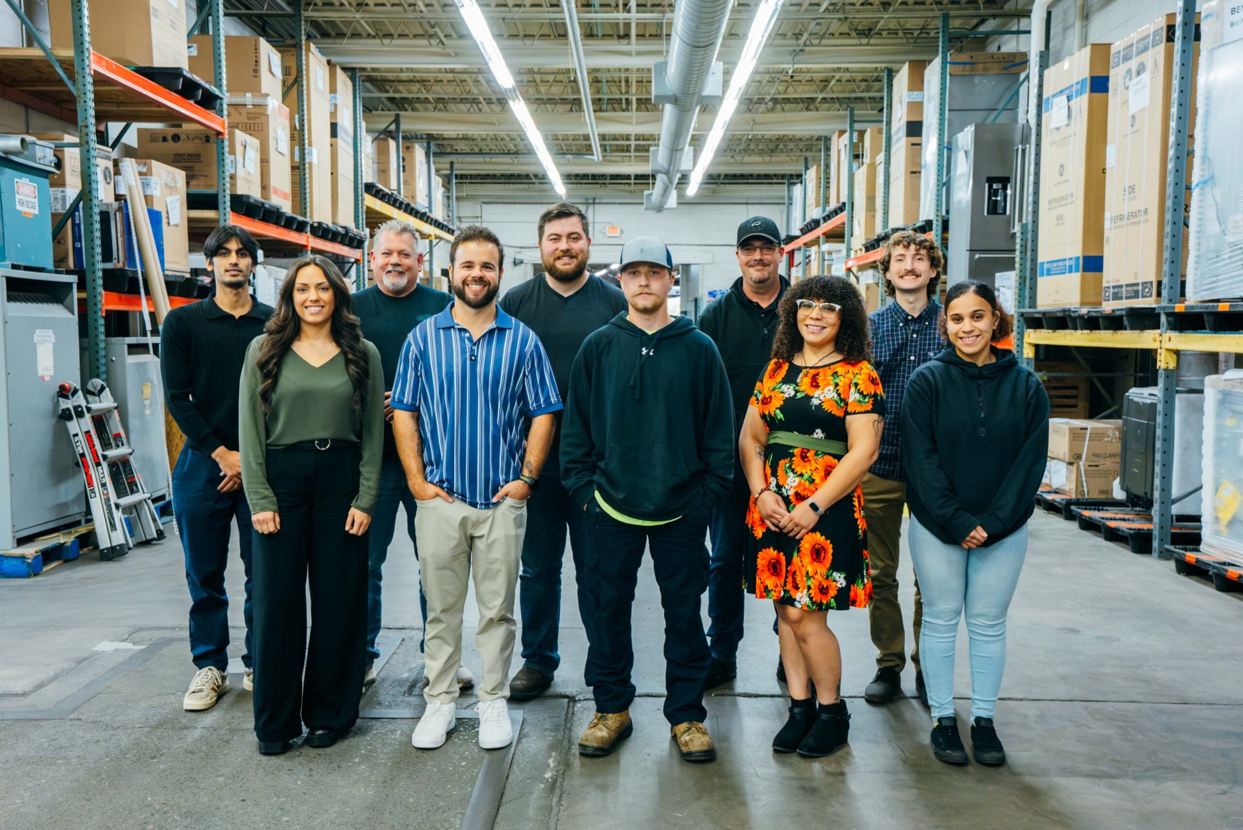 A team of warehouse workers posing in a large storage facility, captured from multiple angles.