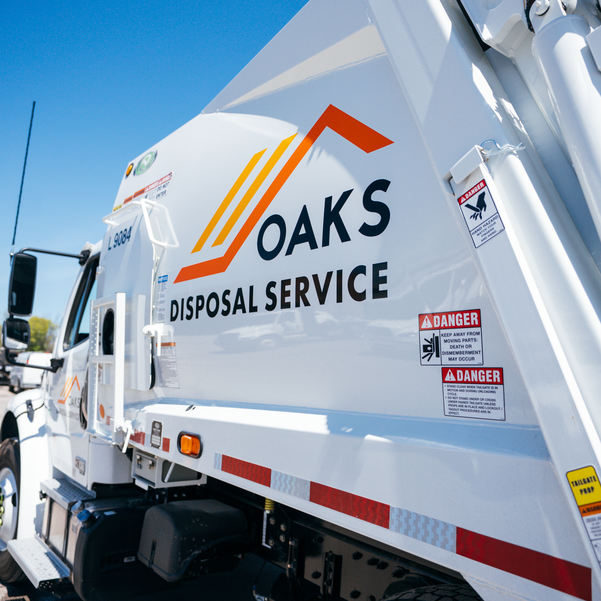 A white garbage truck with Oaks Disposal Service logo