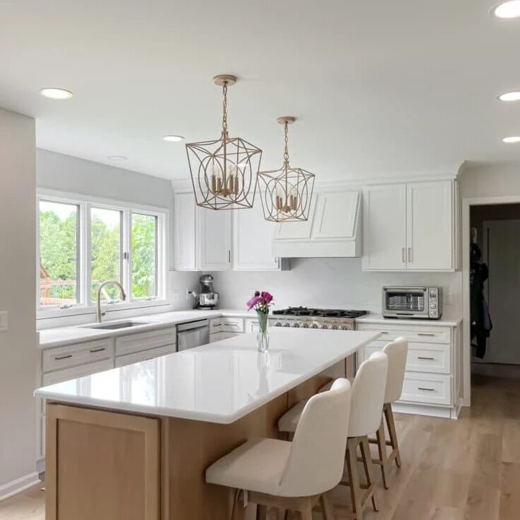 A modern kitchen with white cabinets and a large island with white barstools.
